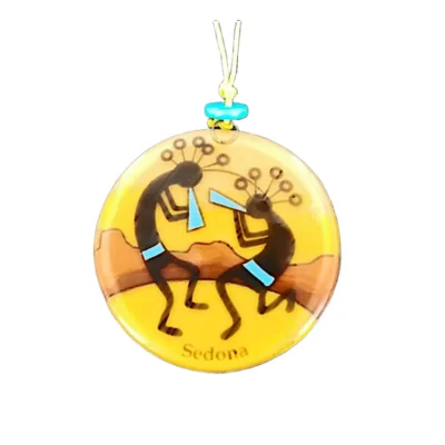 Yellow glass Southwest ornament featuring two black dancing Kokopelli flute players against red rock desert mountains, inscribed with Sedona.