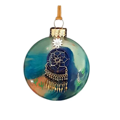 Teal, blue, and terracotta glass Southwest ornament featuring a navy dreamcatcher charm with beaded fringe, gold feathers, and sun emblem.