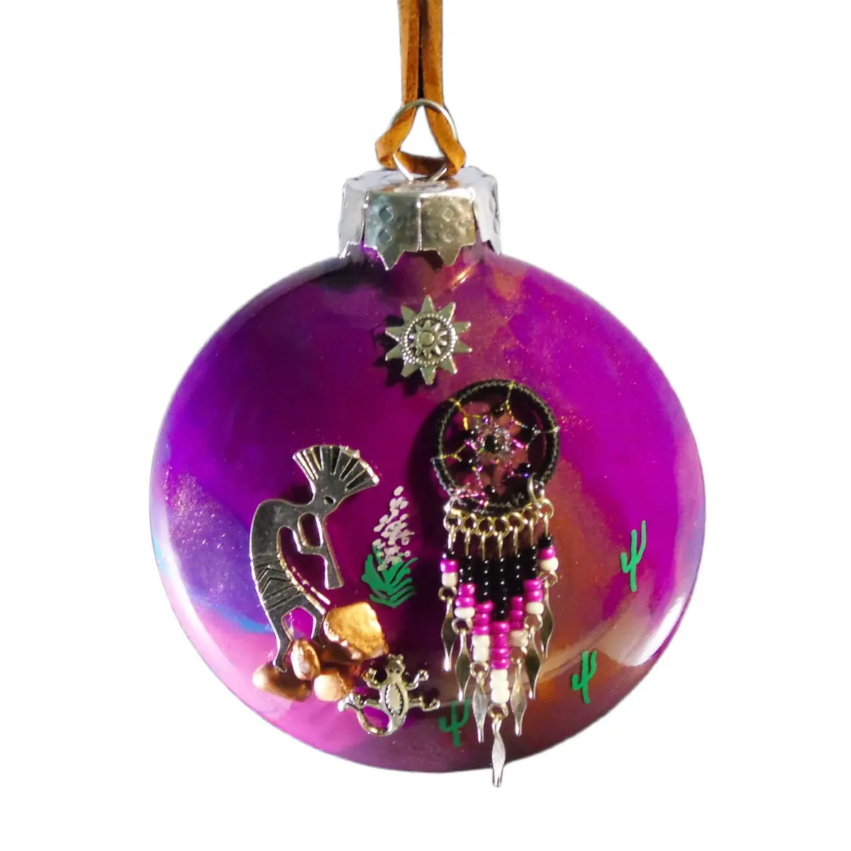 Purple glass Christmas ornament with desert-themed charms: a dreamcatcher, small seahorse, cacti, and beads hanging from a silver cap and brown string.