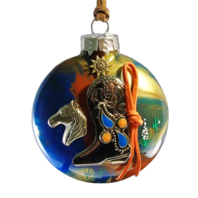Earth-tone glass Western ornament featuring a metallic cowboy boot with turquoise and orange inlaid accents, silver horse head charm, and sun emblem.