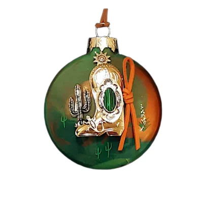 Green and terracotta glass Southwest ornament featuring a gold cowboy boot charm with green malachite-style oval stone, orange suede tie, gold saguaro cactus, lizard, and sun emblem.