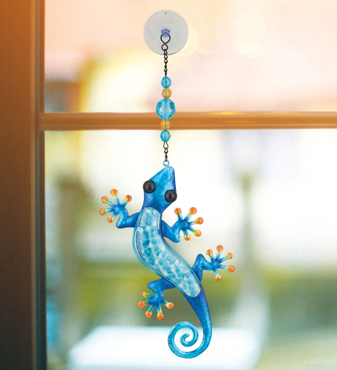 Decorative metal and glass gecko ornament featuring vibrant blue metallic limbs, orange toe accents, and a textured light-blue translucent glass core hanging below a beaded chain.