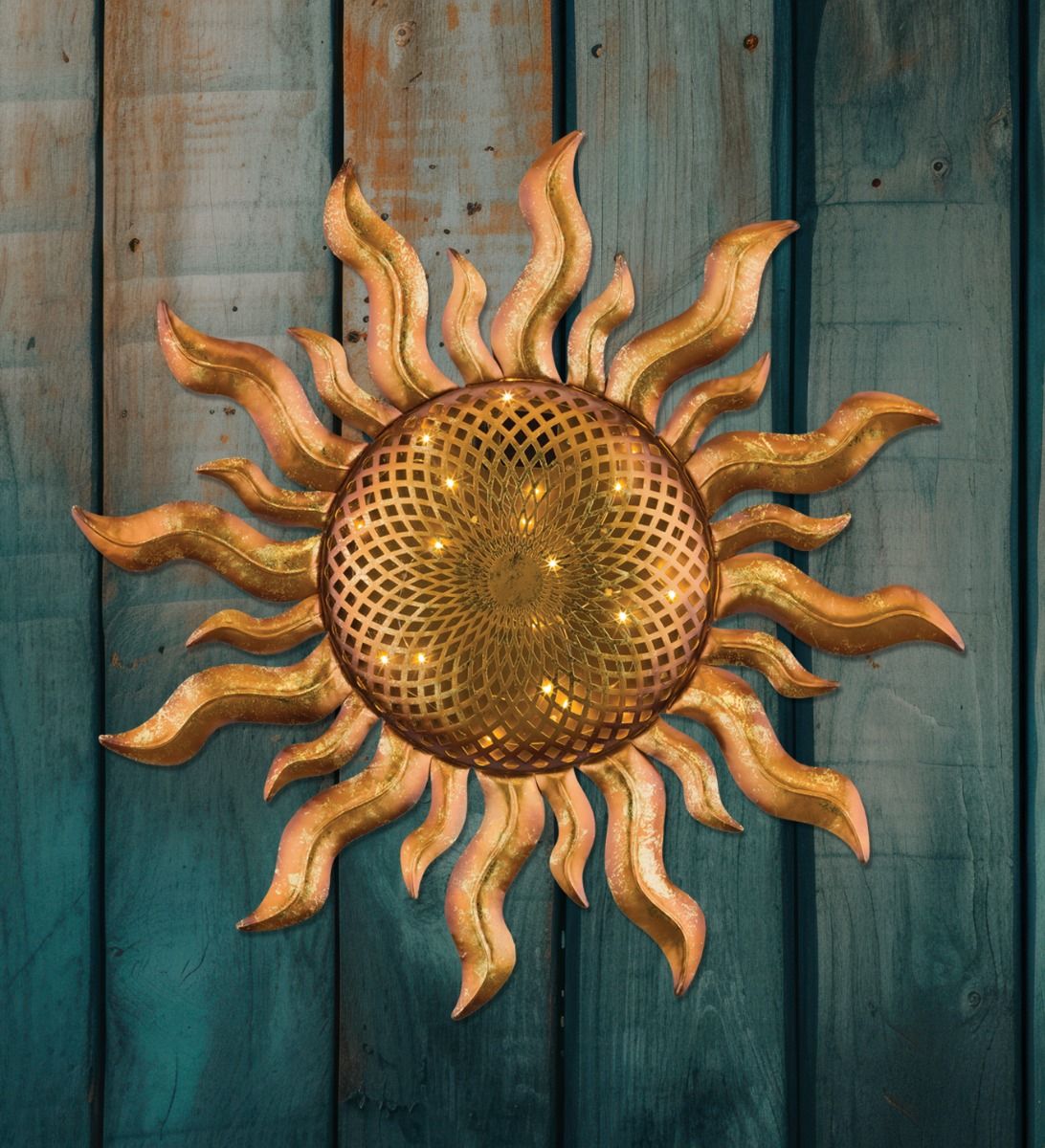 Gold sunburst wall decor with wavy rays mounted on weathered teal wooden boards.