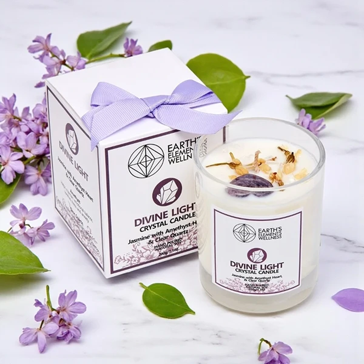 Earth's Elements Divine Light Crystal Candle scented with Jasmine, featuring Amethyst heart and Clear Quartz crystals next to its ribboned gift box.