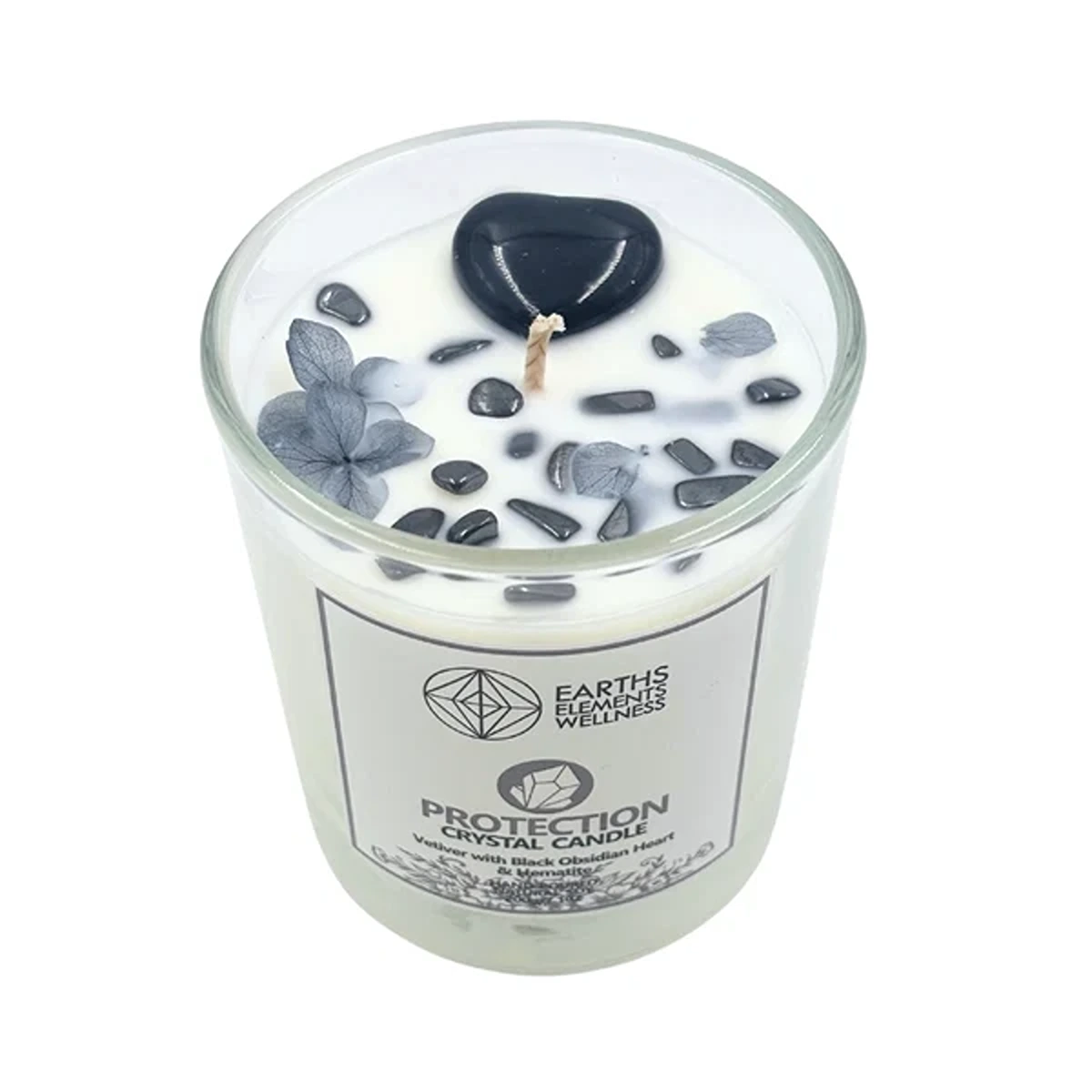 White glass-jar candle labeled "Protection Crystal Candle" with black stone chips and dried leaves on white wax.